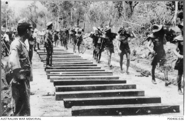 A group of prisoner of wars carrying sleepers along the railway line.